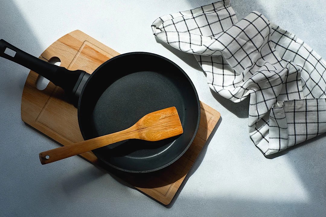 A clean cast-iron skillet sitting on a cutting board and counter.