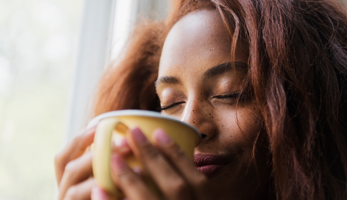 Woman taking deep breath in over fresh cup of hot coffee