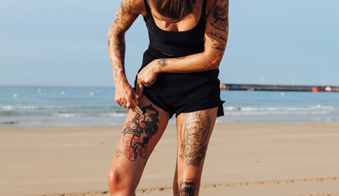 Woman protecting her tattoos with sunblock.