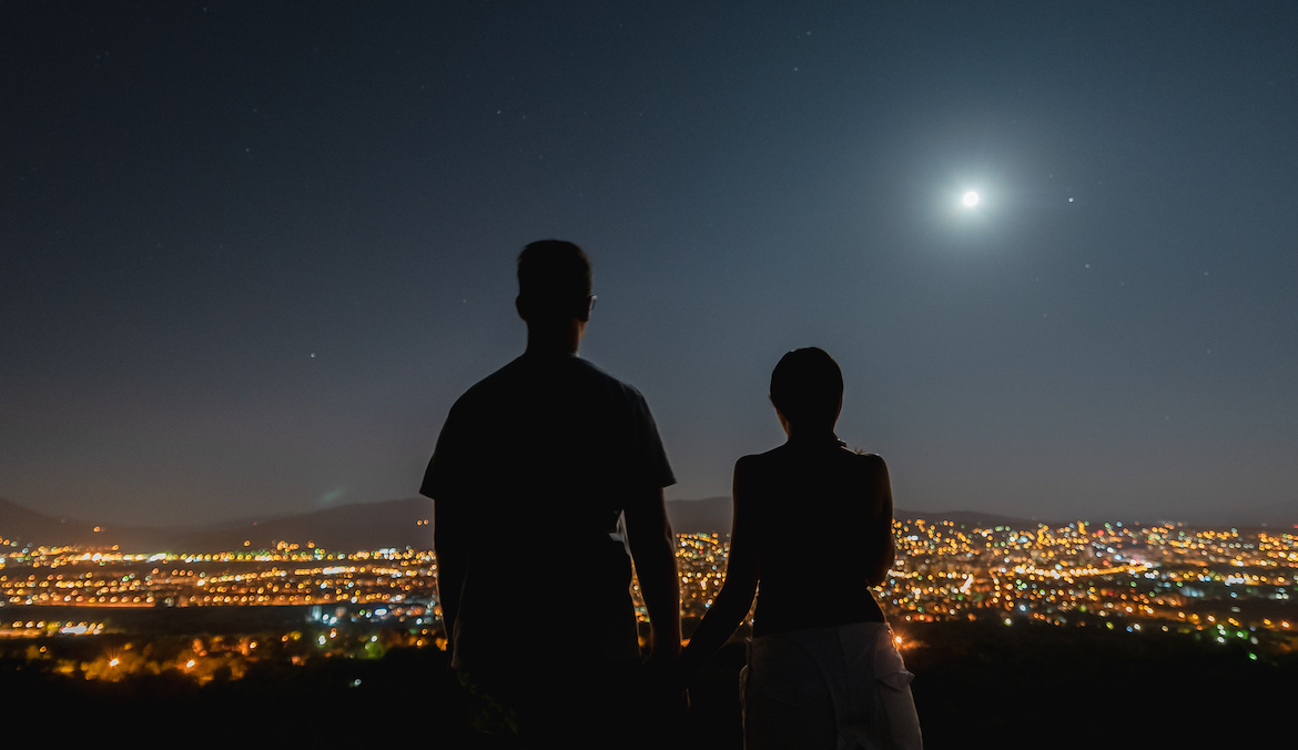 silhouette of a couple looking at the moon