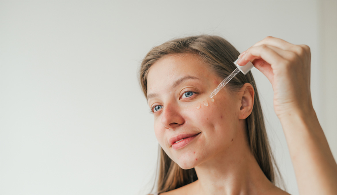 A woman applying a serum to her skin.