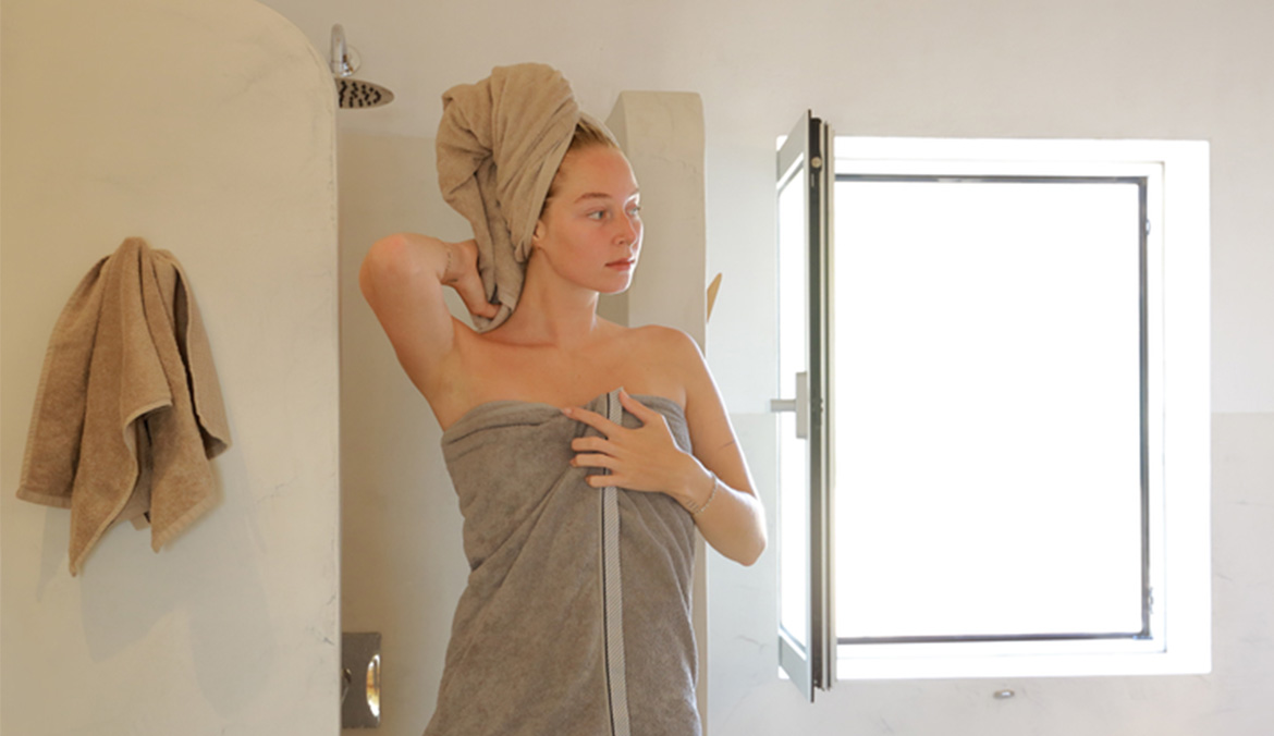 A woman stepping out of the shower wrapped in a towel.