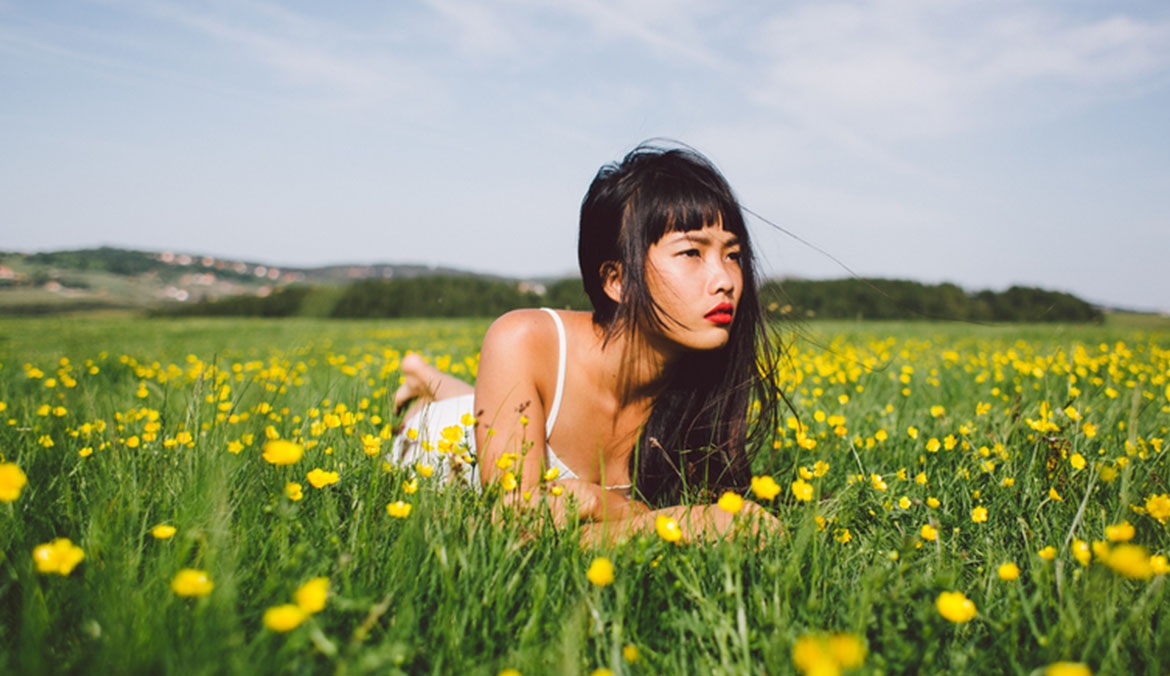 Beautiful young asian woman relaxing on the spring field