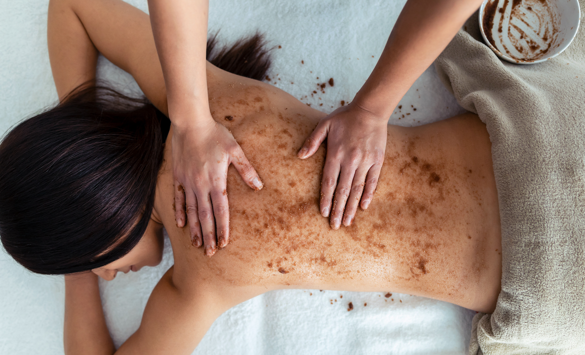 Shot of young woman applying chocolate massage cream with natural ingredients for body treatment to a pretty woman on the spa center.