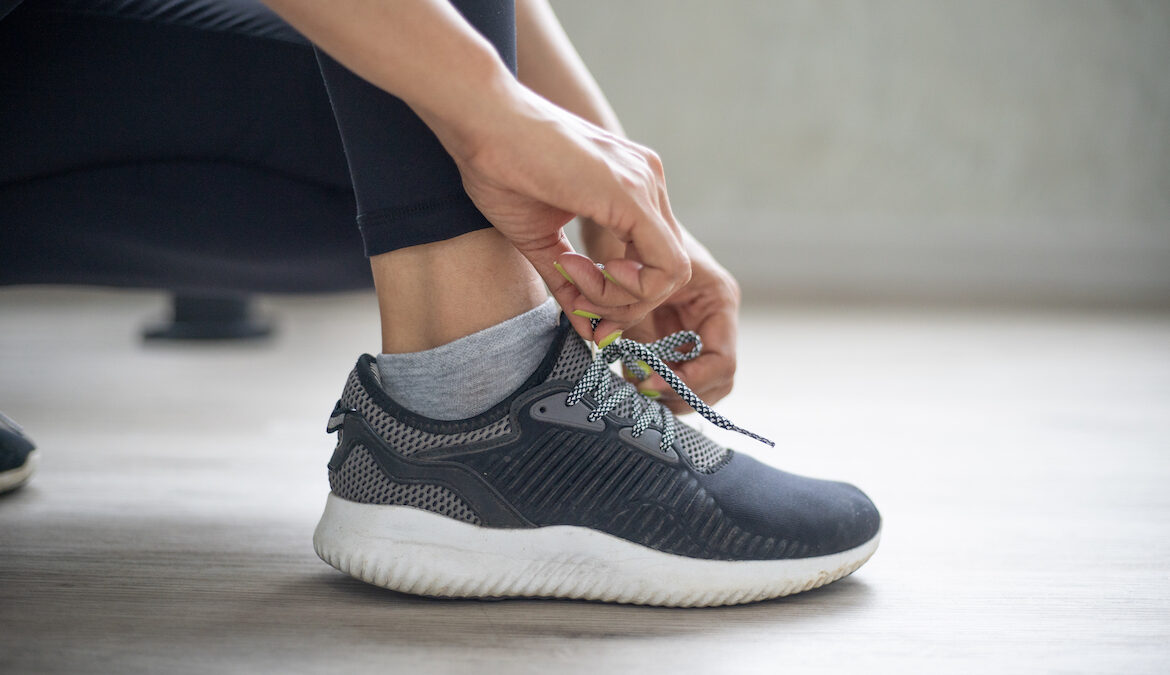 Close-up photo of a woman tying sneaker shoelaces, best orthopedic shoes for women