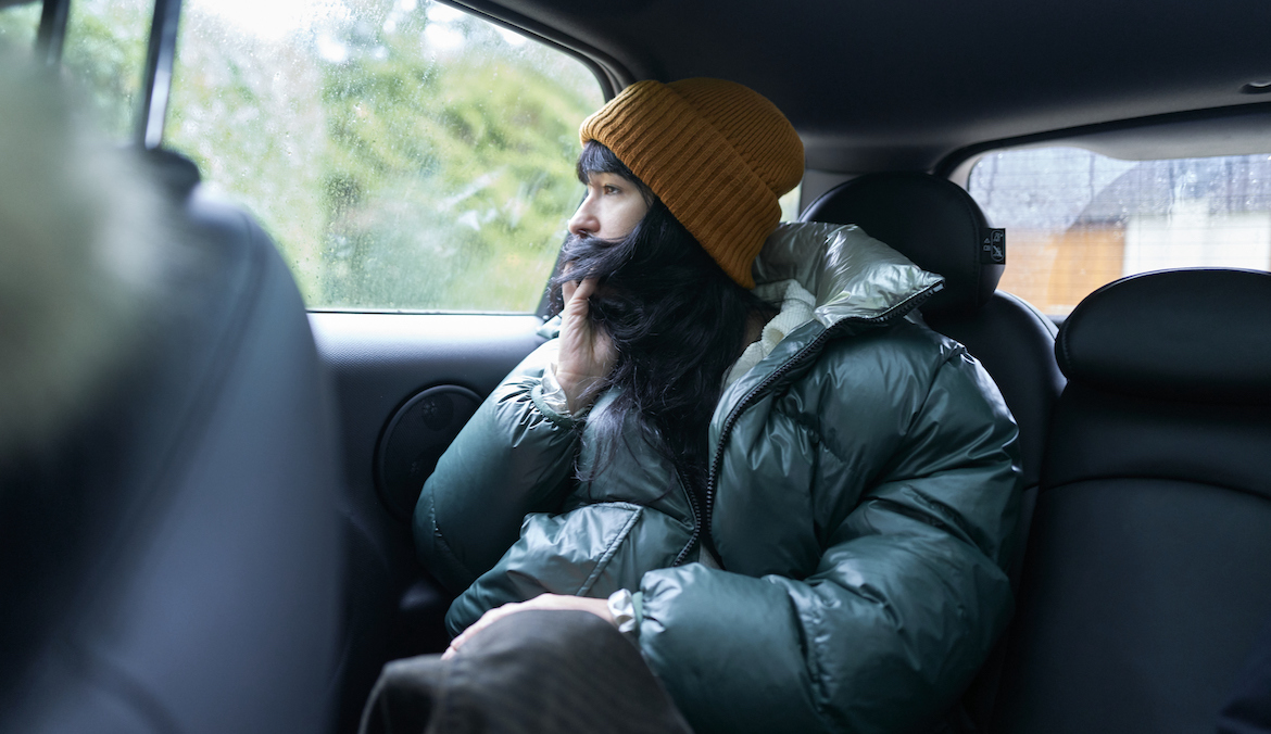 Woman sitting in back seat of car on cold winter rain day