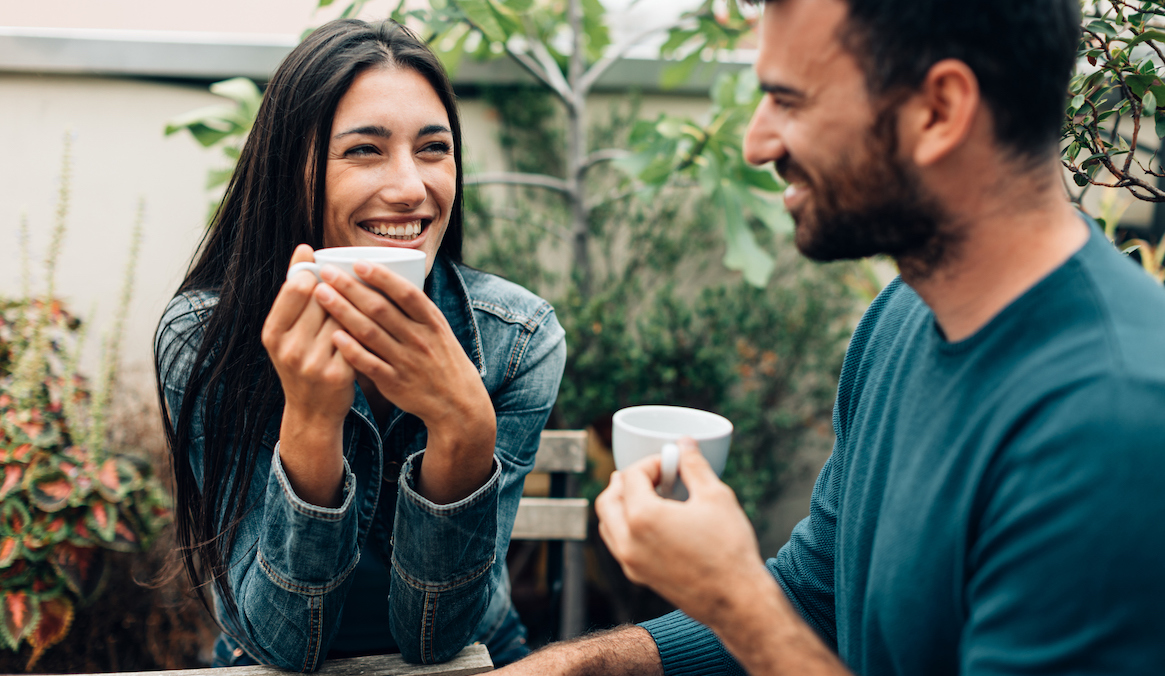 A man and woman sit and have coffee together.