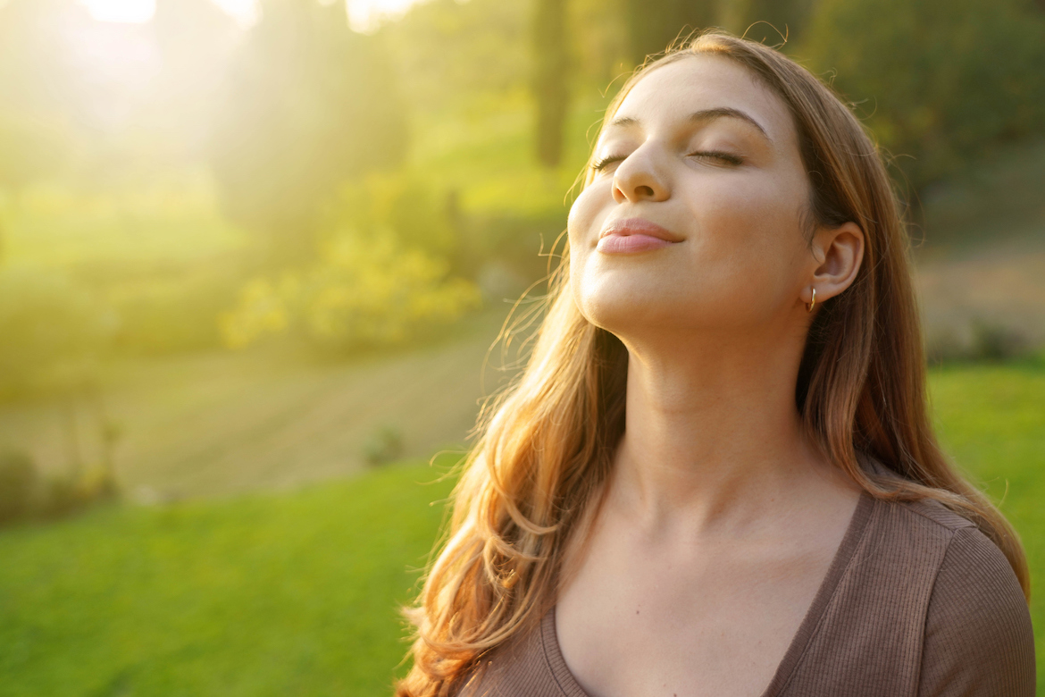 A woman smiles and closes her eyes as the sun hits her face.