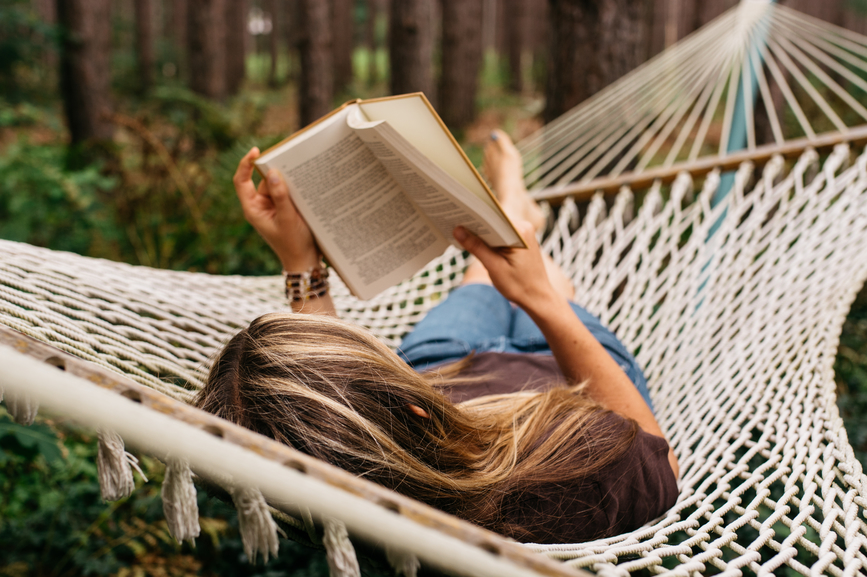 Woman reading a book in a hammock.