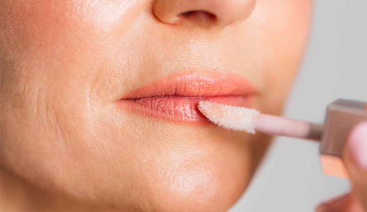 A woman applying lip gloss.