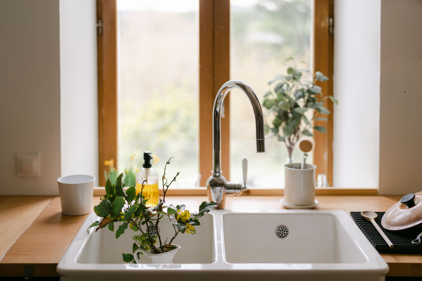 Farmhouse kitchen sink in front of a window with flowers and wooden counter tops.