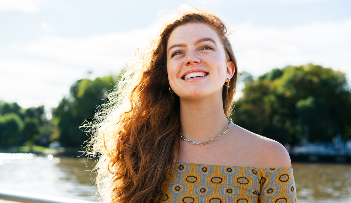 Smiling woman with red hair standing by a lake
