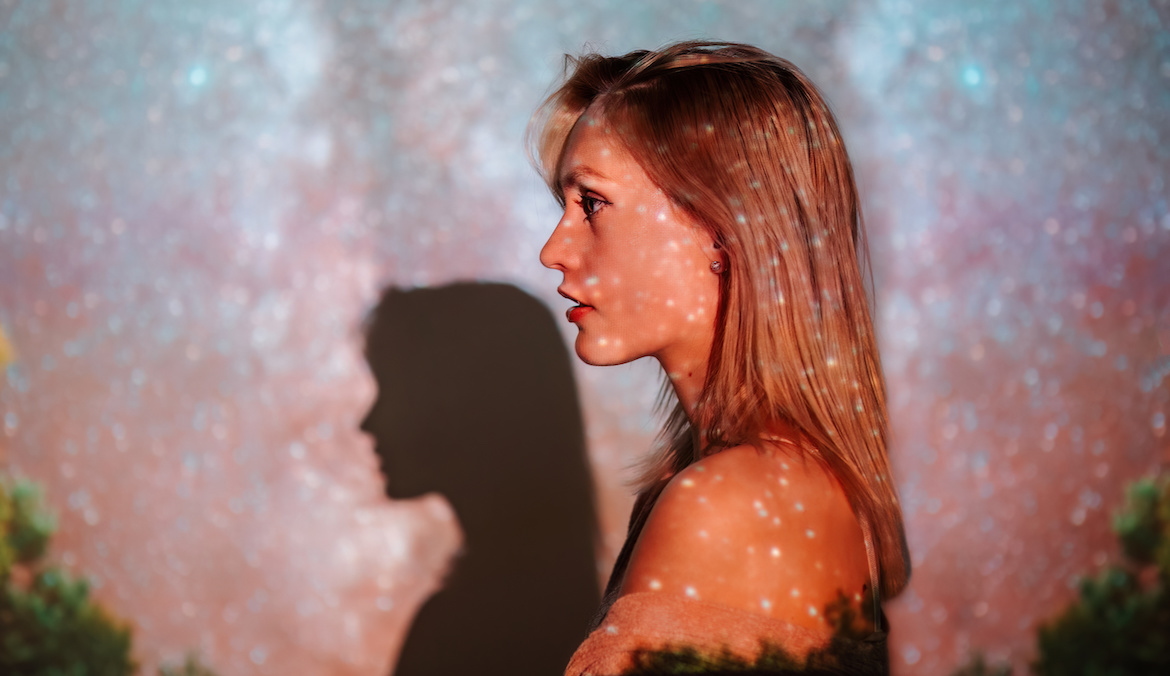 Blonde woman standing in front of celestial background