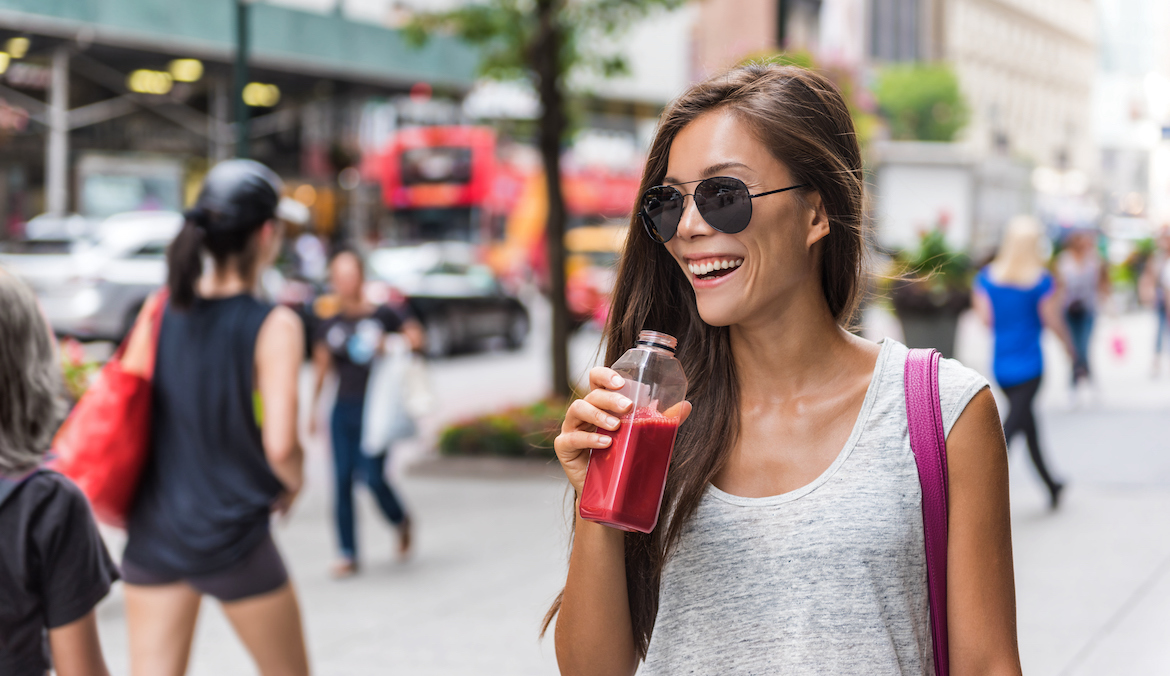 hipster asian woman drinking beetroot juice walking in New York City