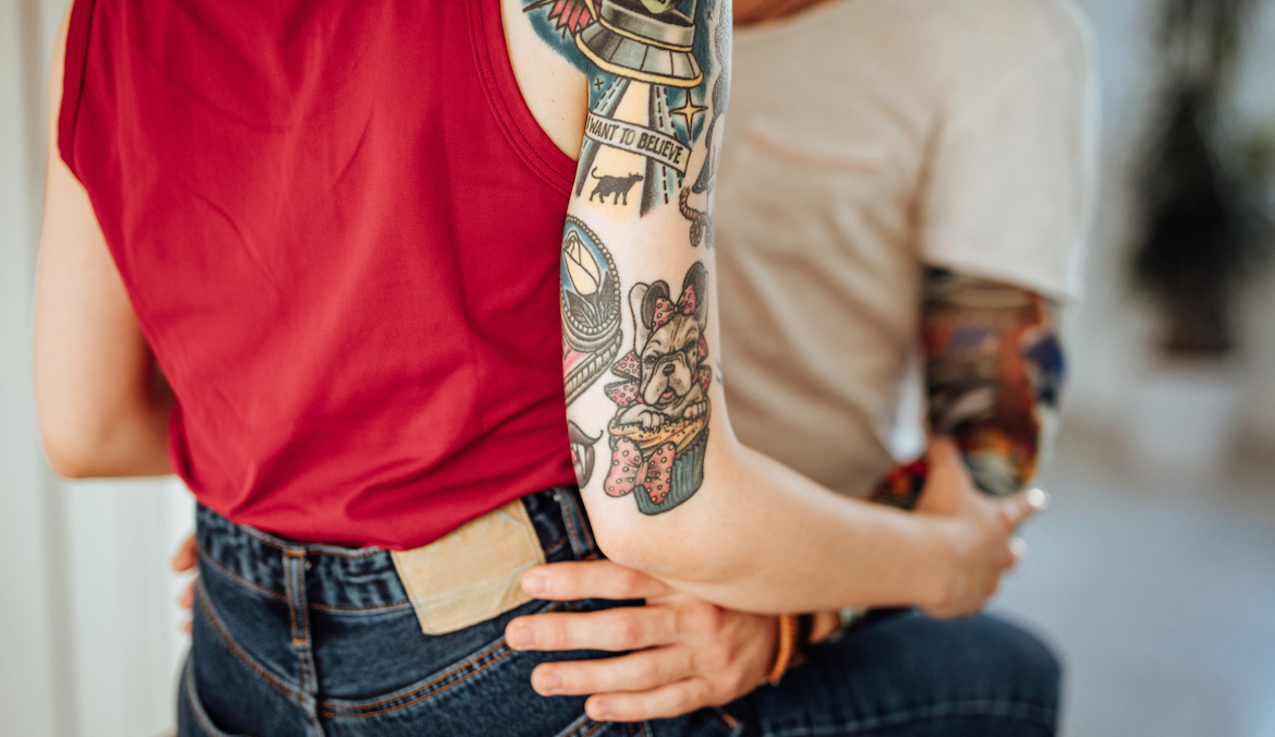 woman with sleeve tatoos embracing man with tattoos