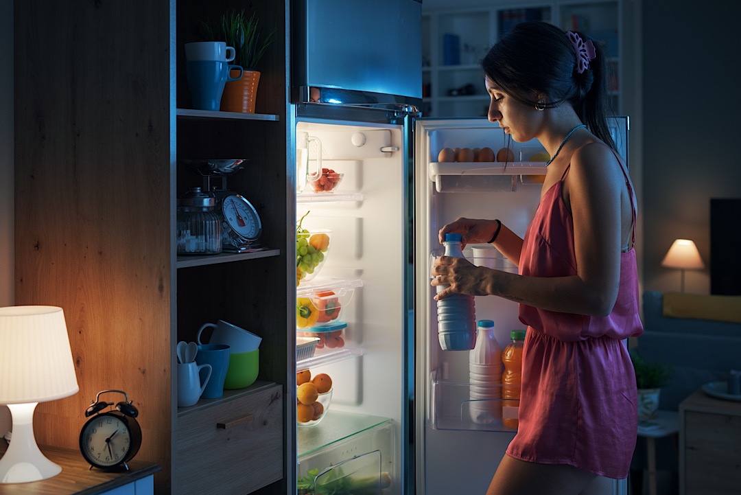 Woman getting milk out of fridge at night