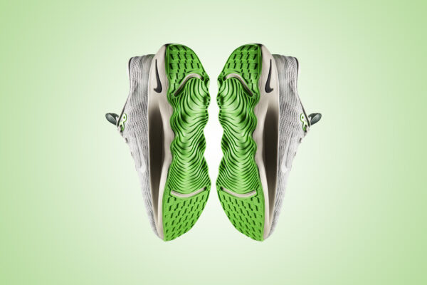 A pair of tennis shoes seen from the bottom, showing a neon green sole with lots of grooves.