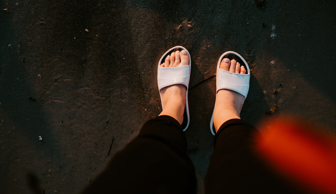 woman wearing slide on sandals, like the apl zig zag slides, at the beach