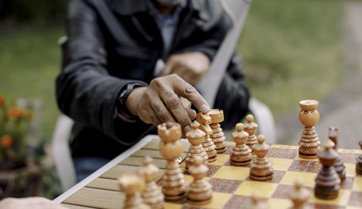 A senior man playing chess in park.