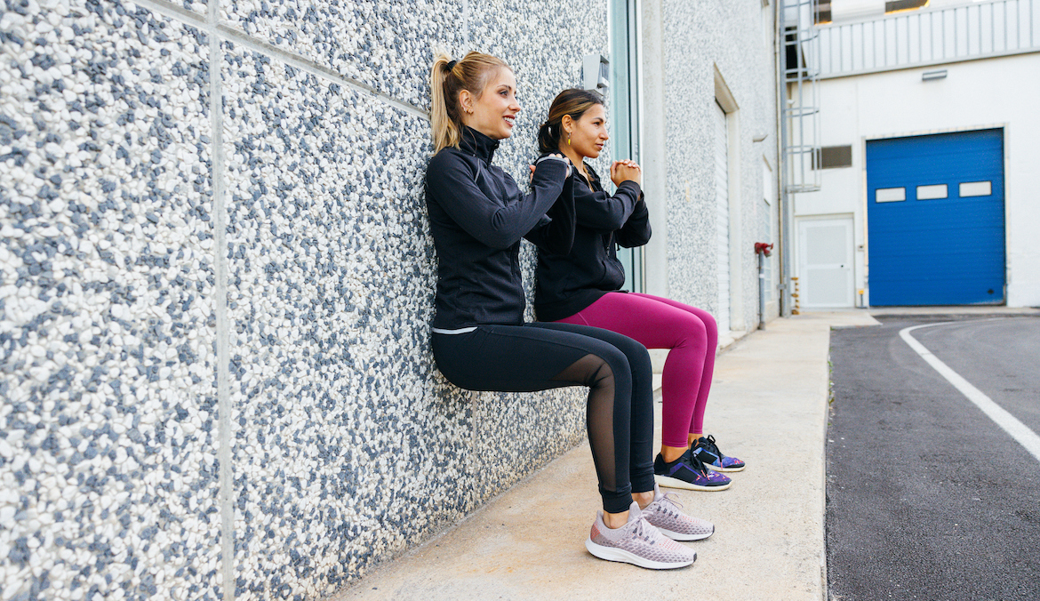 Two women doing a wall sit isometric exercise for blood pressure