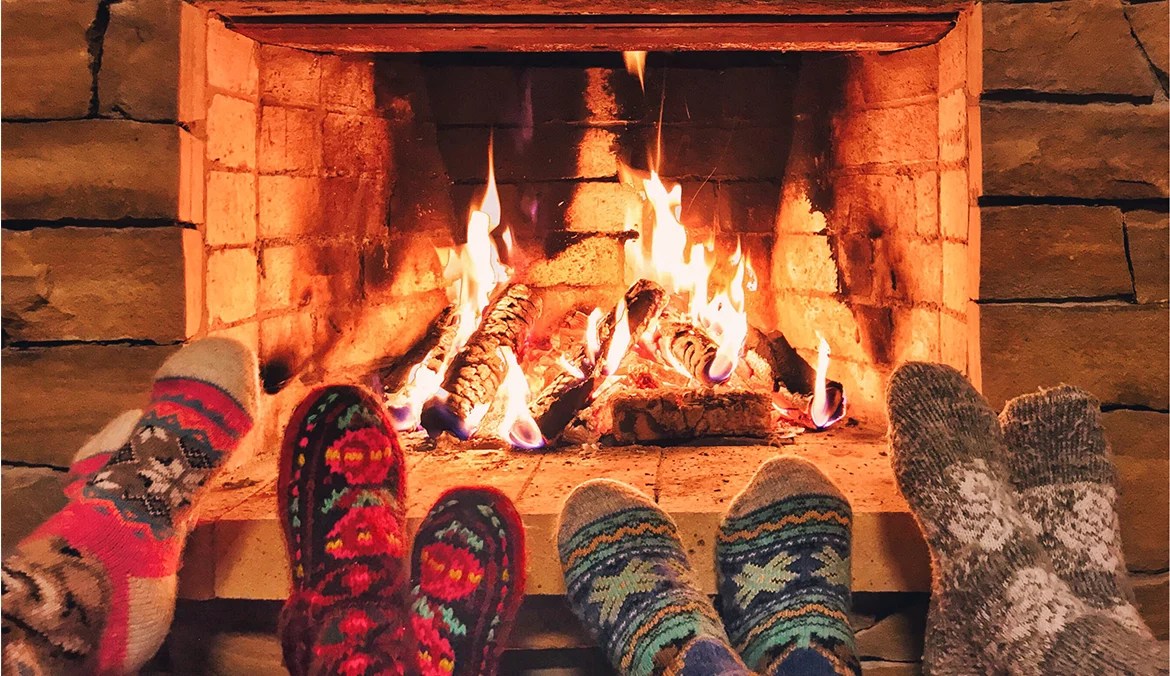 feet by a cozy fireplace with winter decor