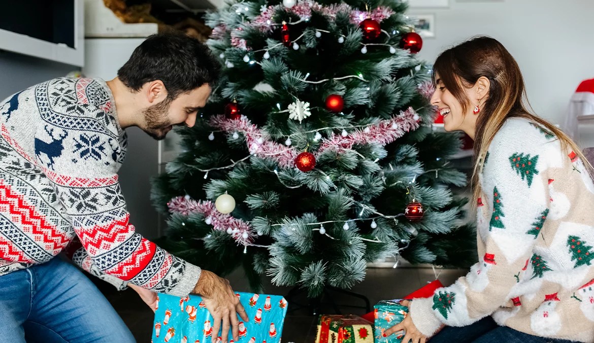couple putting personalized gifts under their christmas tree