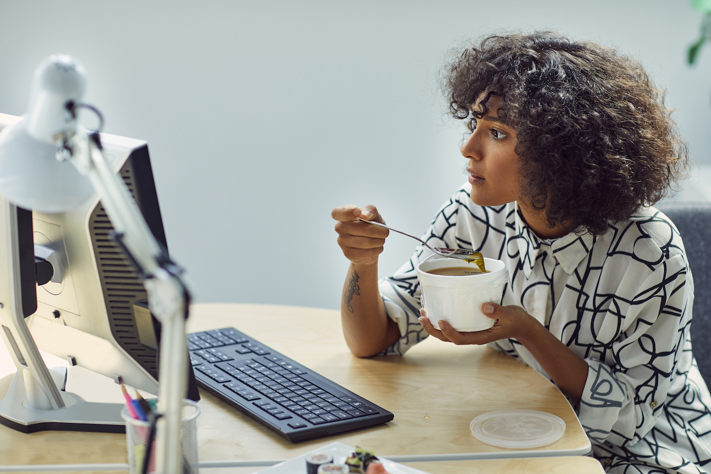 Woman eating soup at her desk.