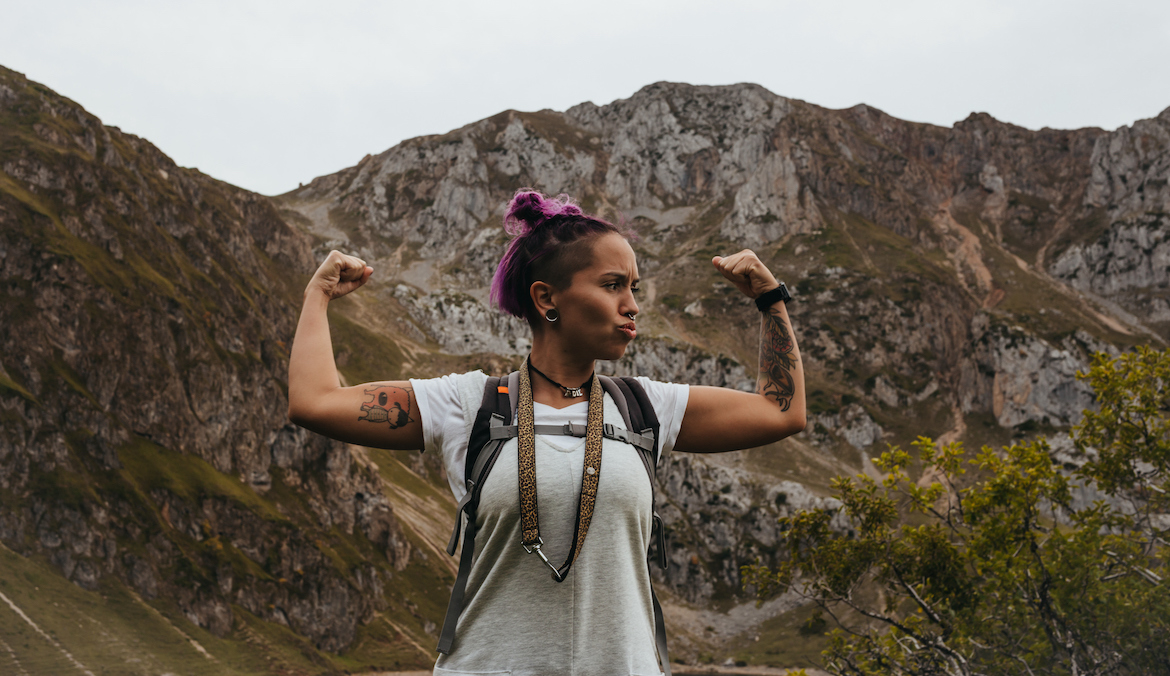 A woman flexing her bicep on a hot girl hike