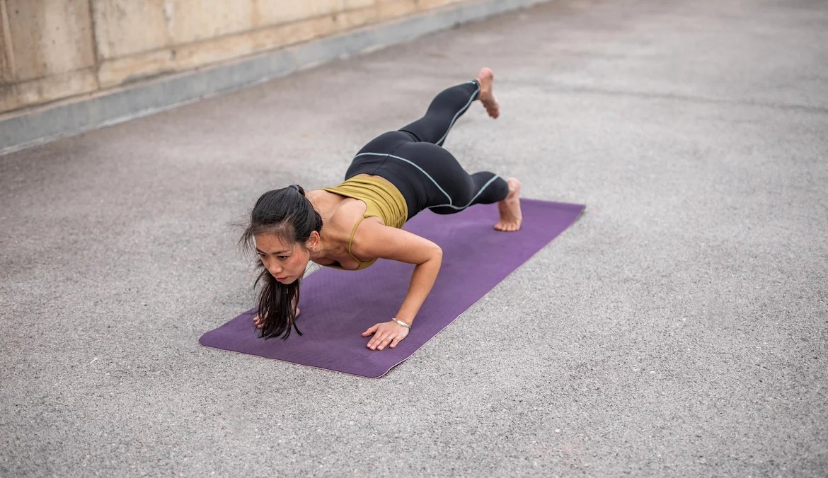 Woman building mental endurance as she does a one-legged pushup on a yoga mat