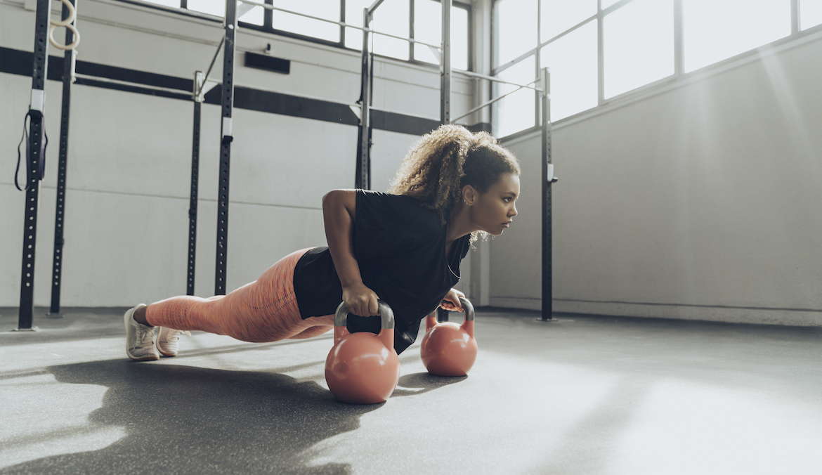 A woman doing a plank during a core kettlebell workout.