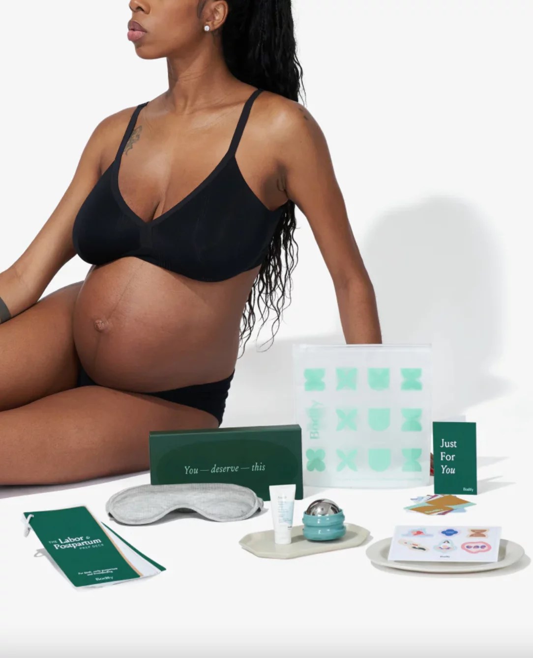 A pregnant woman in black lingerie with self-care items.