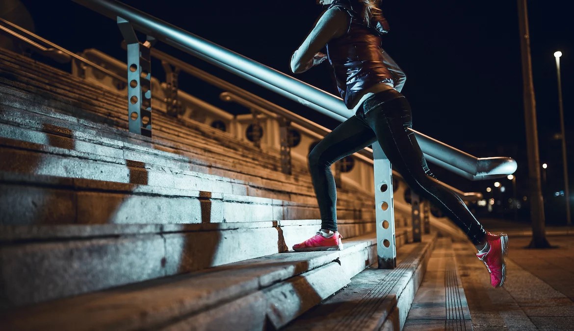 A woman running up stadium stairs at night.