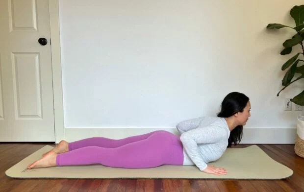 yoga teacher with long dark hair demonstrates how to do baby cobra in yoga on a mat