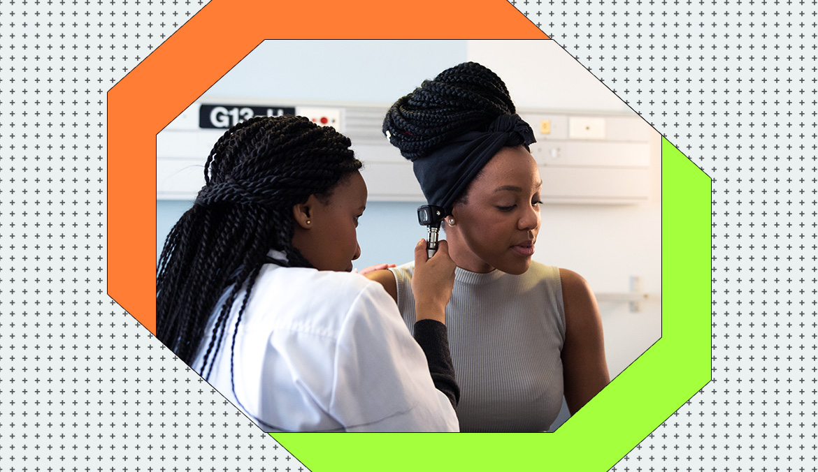 A doctor with long black braids looking into a patient's ear, to represent how often you should get a physical exam