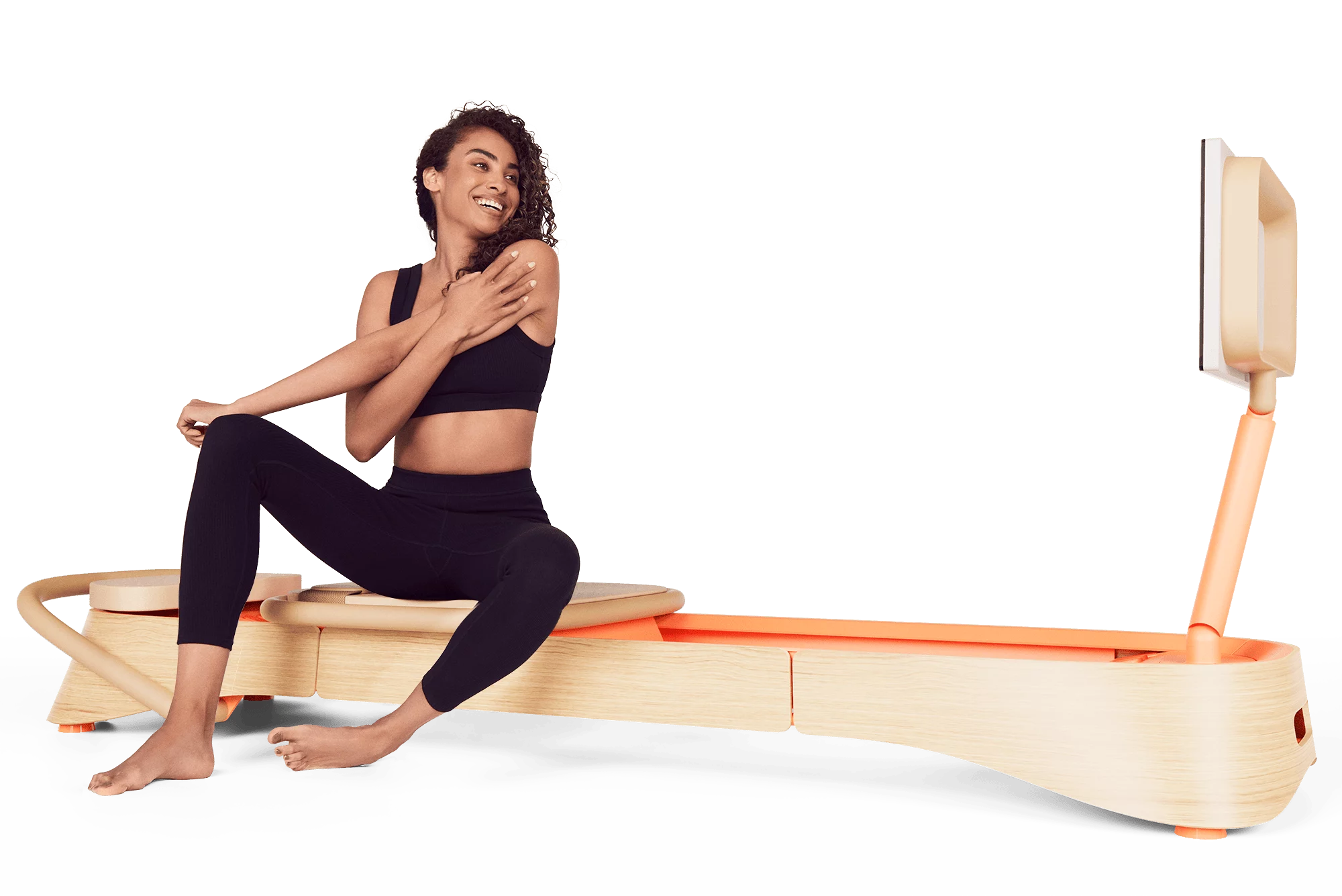 A person sitting on a pink frame reformer at-home pilates equipment