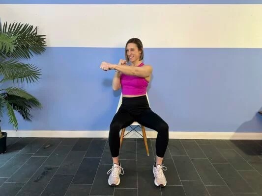 Personal trainer demonstrating seated cross-body punch in chair