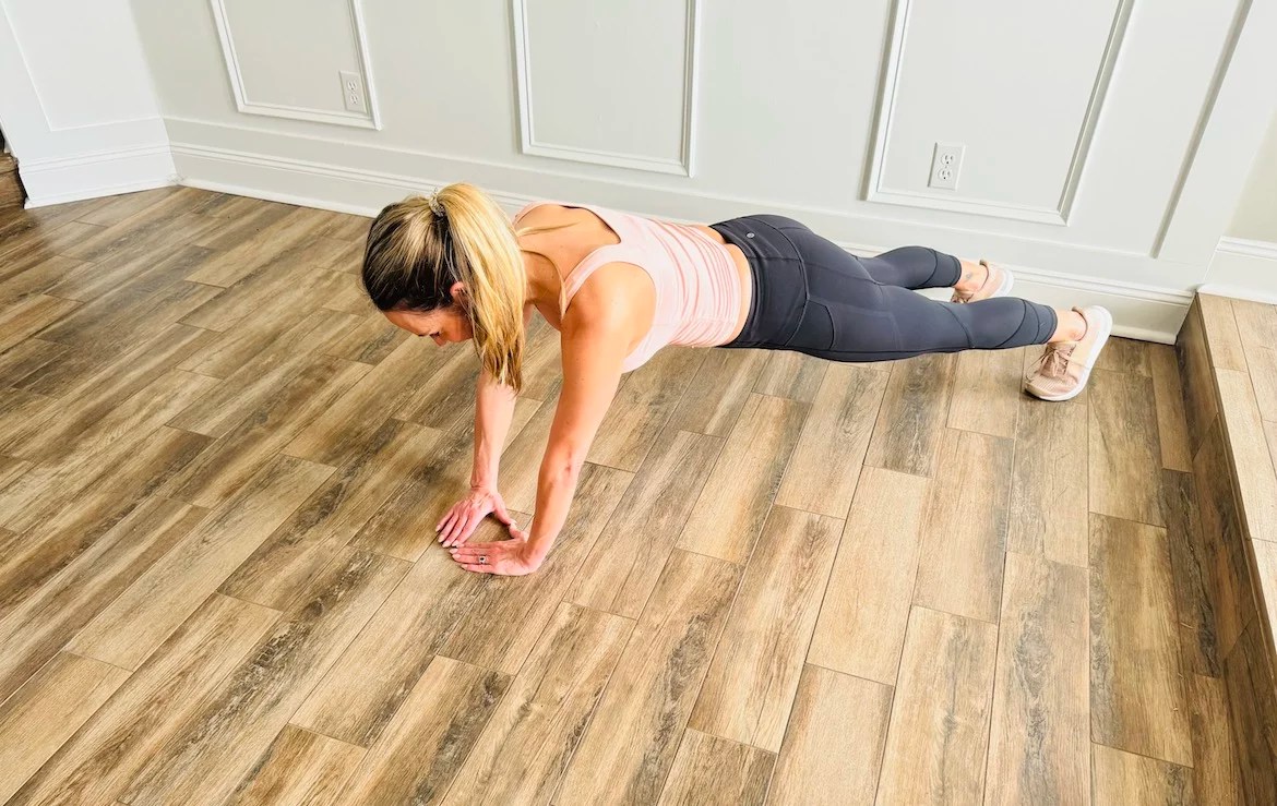 female PT with a blond ponytail wearing a tank top and leggings shows how to get into diamond push-up form
