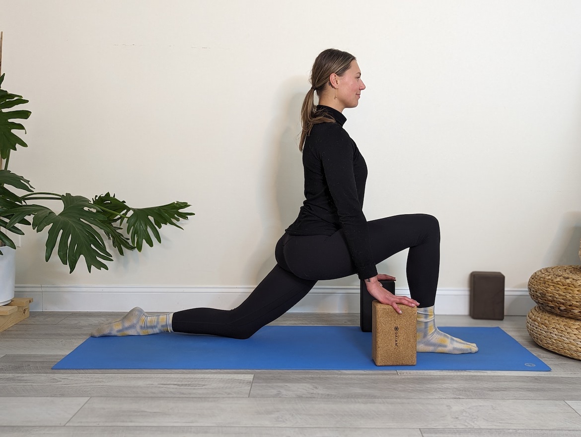 Yoga teacher demonstrating low lunge with yoga blocks