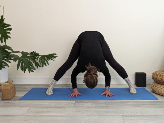 Yoga teacher demonstrating standing wide-legged forward fold