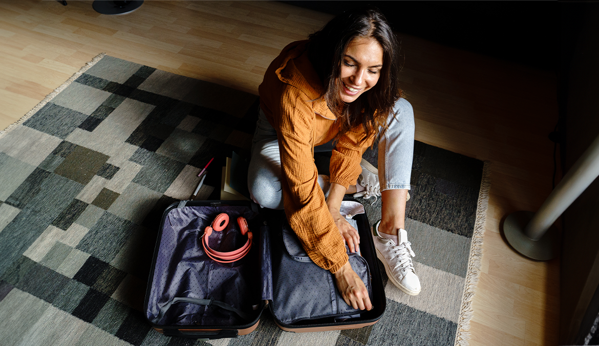 woman packing her suitcase, including a knit blanket