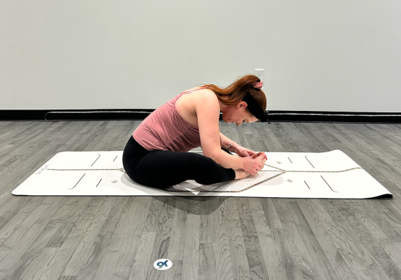 Yoga teacher demonstrating butterfly pose with forward bend