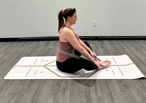 Yoga teacher demonstrating butterfly pose with strap