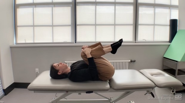 Physical therapist demonstrating double knee-to-chest stretch