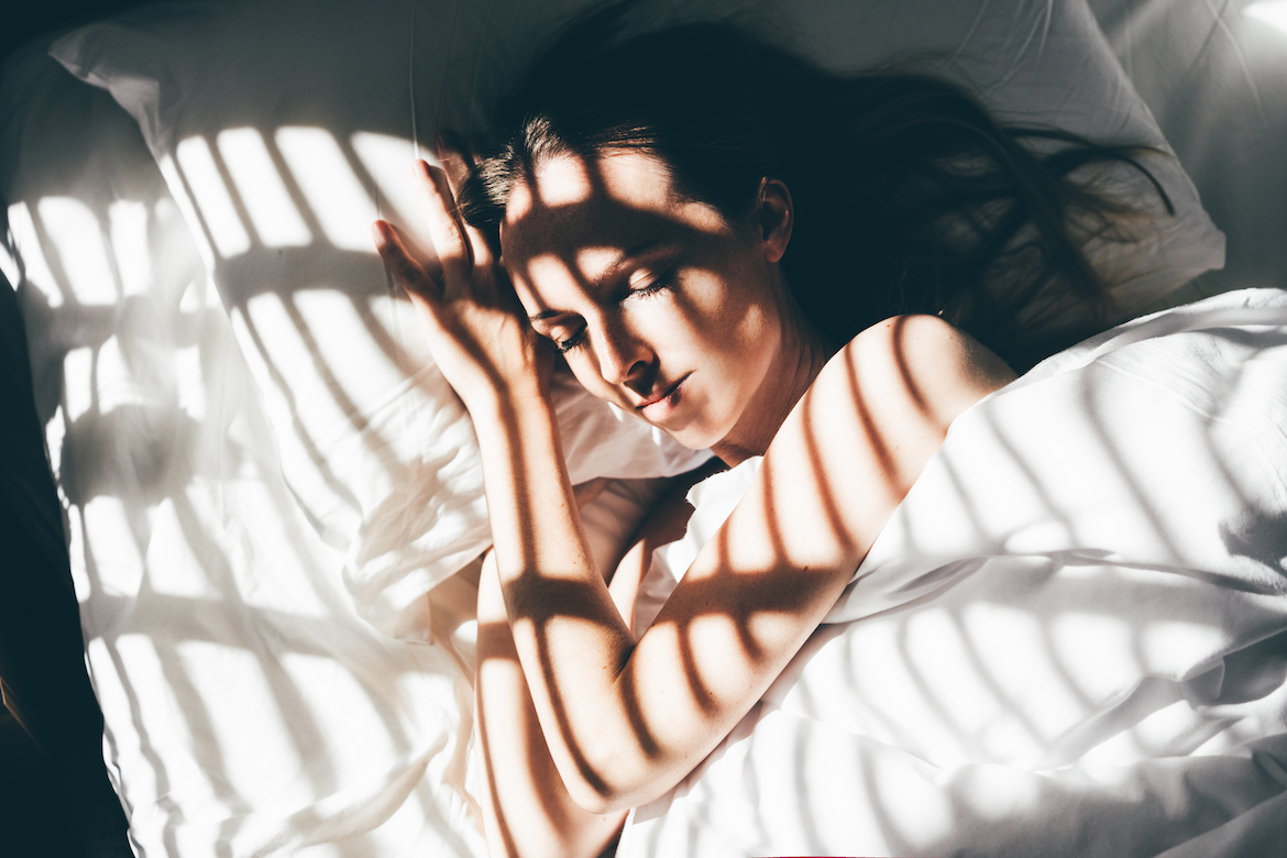 Beautiful young woman sleeps in a comfortable bed. Sunbeam of dawn on her face. Using one of the best silk pillowcases for hair