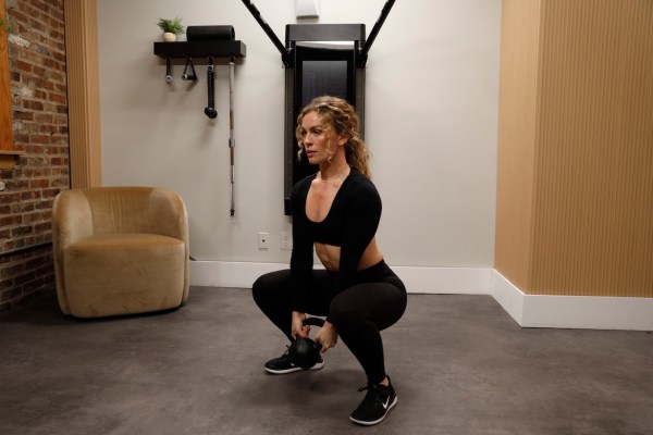 Personal trainer demonstrating goblet squat with biceps curl