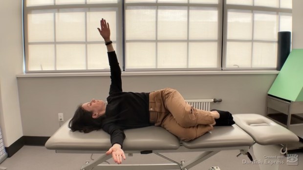 Physical therapist demonstrating open-book stretch