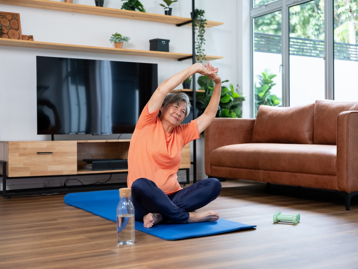 Older adult stretching on yoga mat at home, part of a Radio Taiso mobility routine