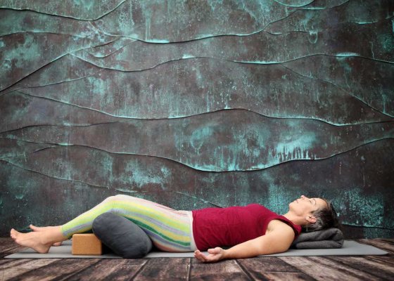 Yoga teacher demonstrating supported corpse pose