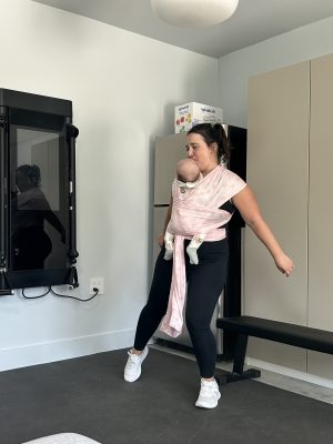 The reviewer doing one of Sculpt Society's baby-wearing workouts, dancing with a baby strapped to her chest.