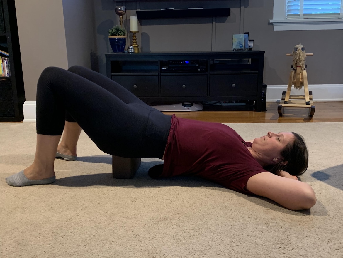 female physical therapist demonstrates how to do a supported bridge pose for psoas release